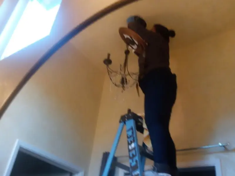 Electrician installing a chandelier in a Lely Resort residence
